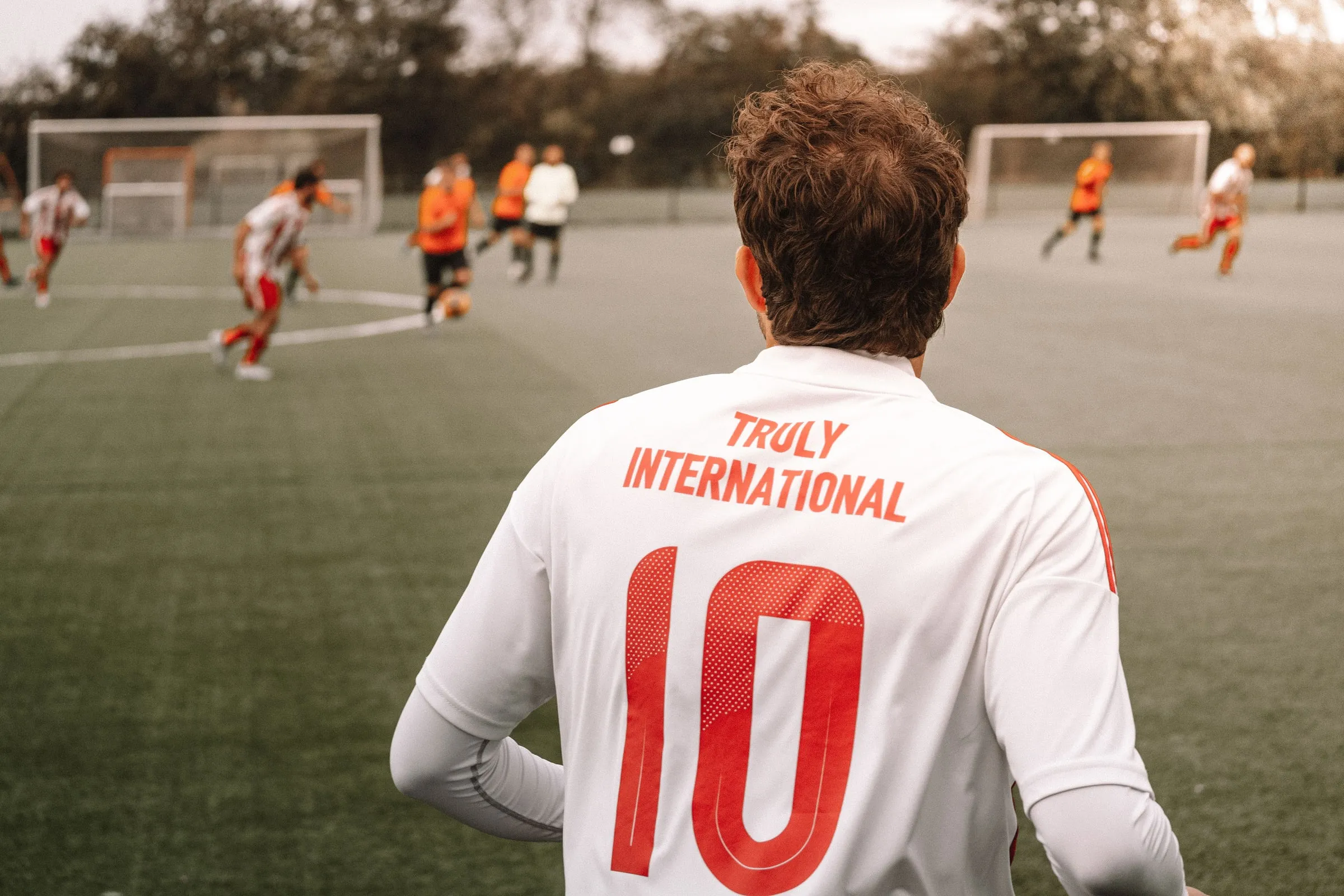 Back of a white shirt with the number 10 and the words Truly International, with a match in the background