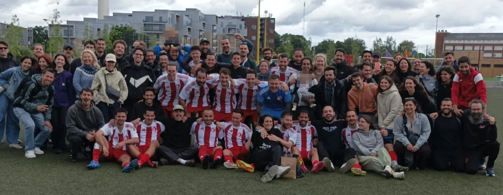 Players in red and white celebrate on the pitch with friends, partners and families